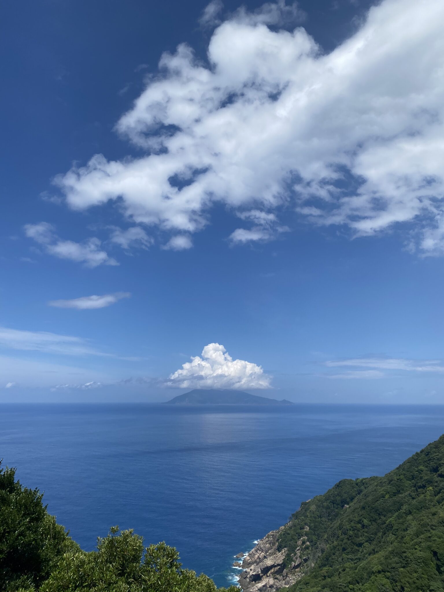 Pacific Ocean view from a Yakushima coastal pull-off with distant Kuchinoerabu island