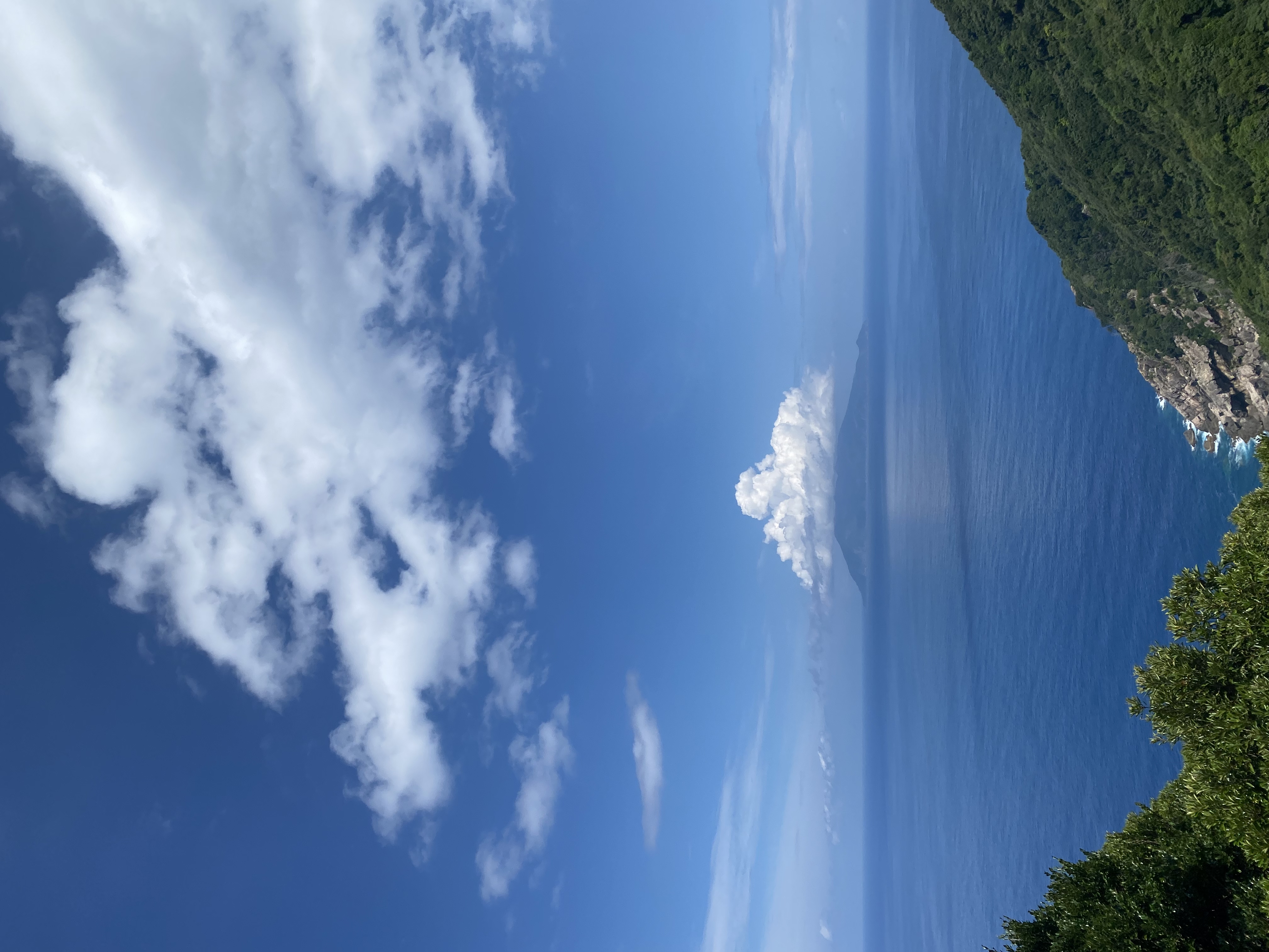 Pacific Ocean view from a Yakushima coastal pull-off with distant Kuchinoerabu island