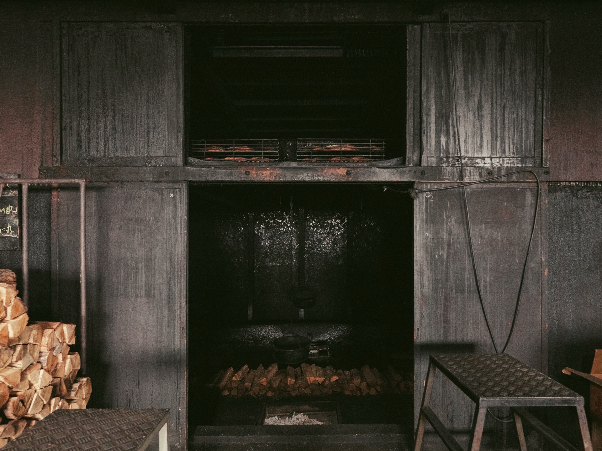The smoke chamber at Yamaju with neatly stacked firewood logs visible inside the open chamber door