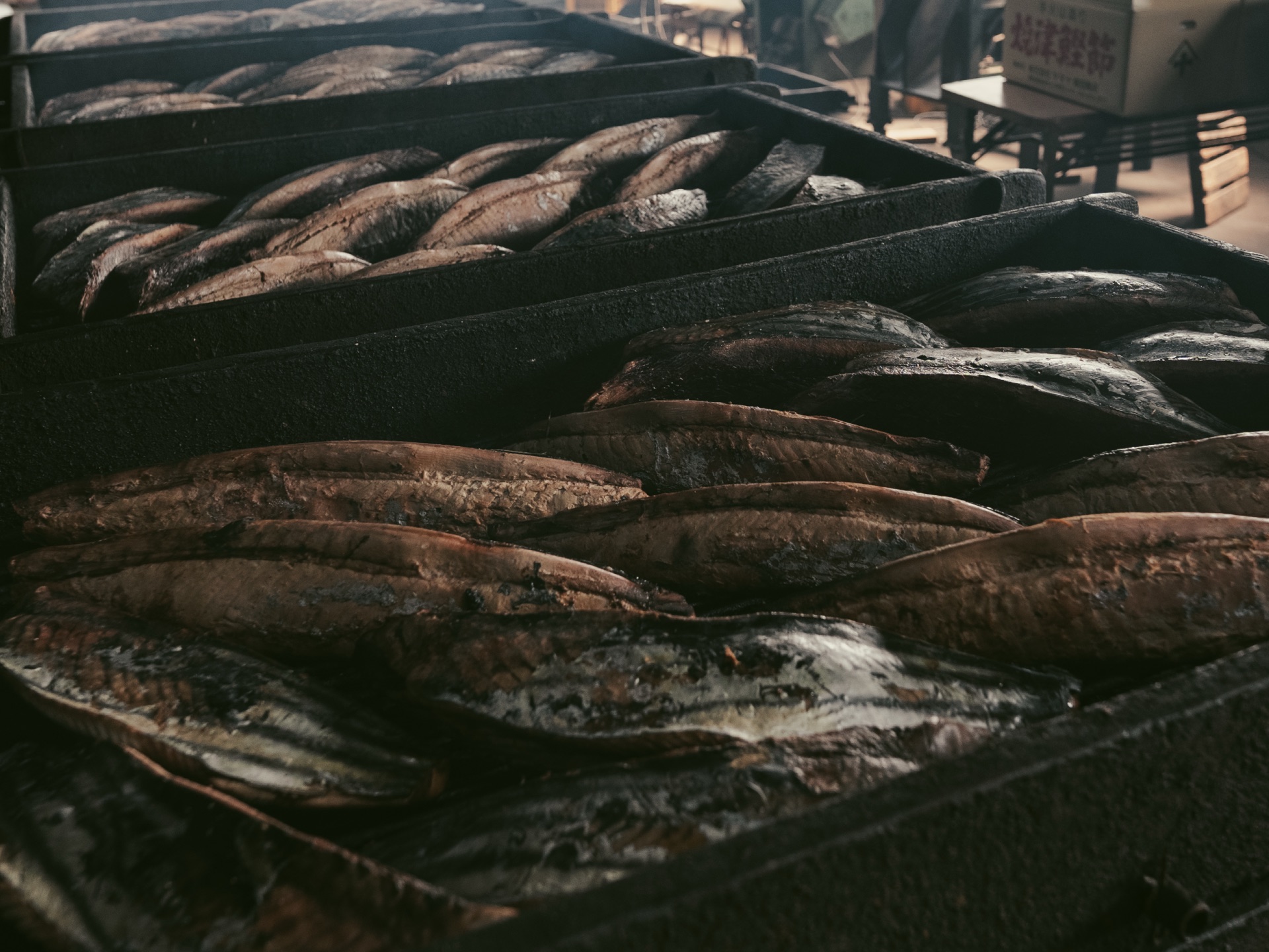 Trays of fully smoked bonito loins stacked in the workshop ready for the next stage of curing