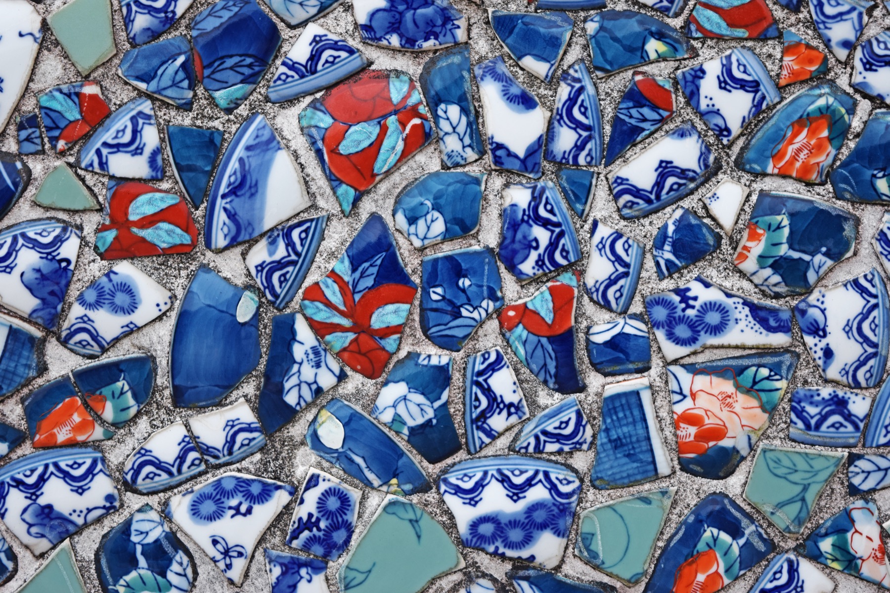 A wall covered in a mosaic of broken Arita and Imari porcelain shards in cobalt blue, iron red, white and celadon green, a decorative feature made from porcelain fragments in Arita, Saga