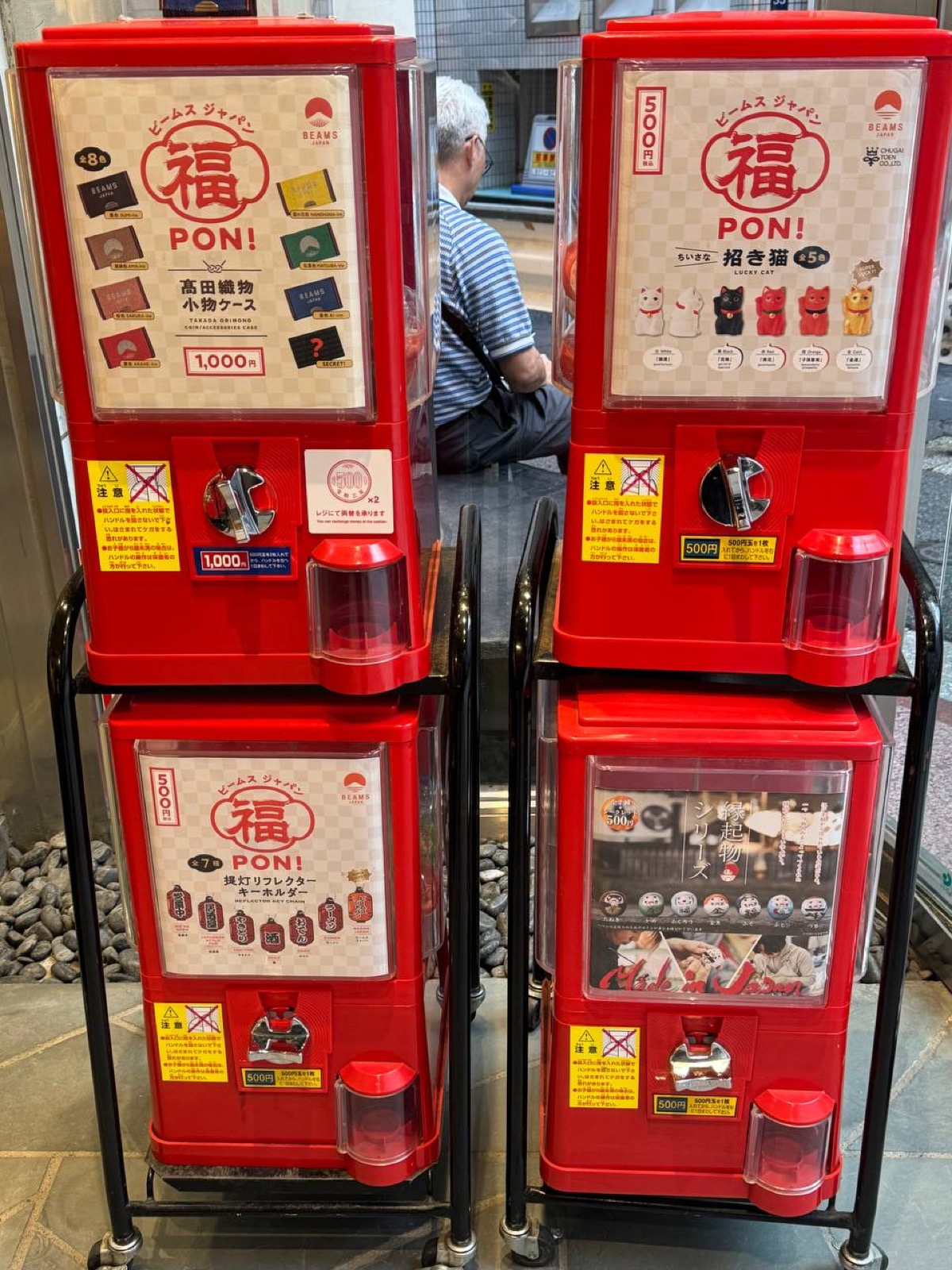 Red 'BEAMS JAPAN Fuku PON!' original capsule-toy machines selling items like a Takada-textile pouch and maneki-neko miniatures inside the Shinjuku store.