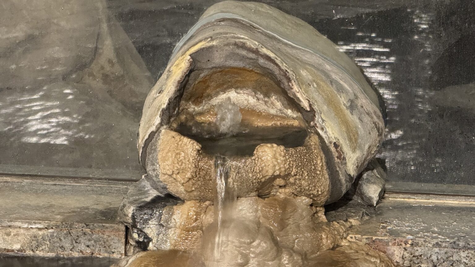 A natural mineral deposit formation at Club Wyndham Chikumakan where hot-spring water pours over a thick yellow-brown crust of spring minerals, in Togura-Kamiyamada Onsen, Nagano