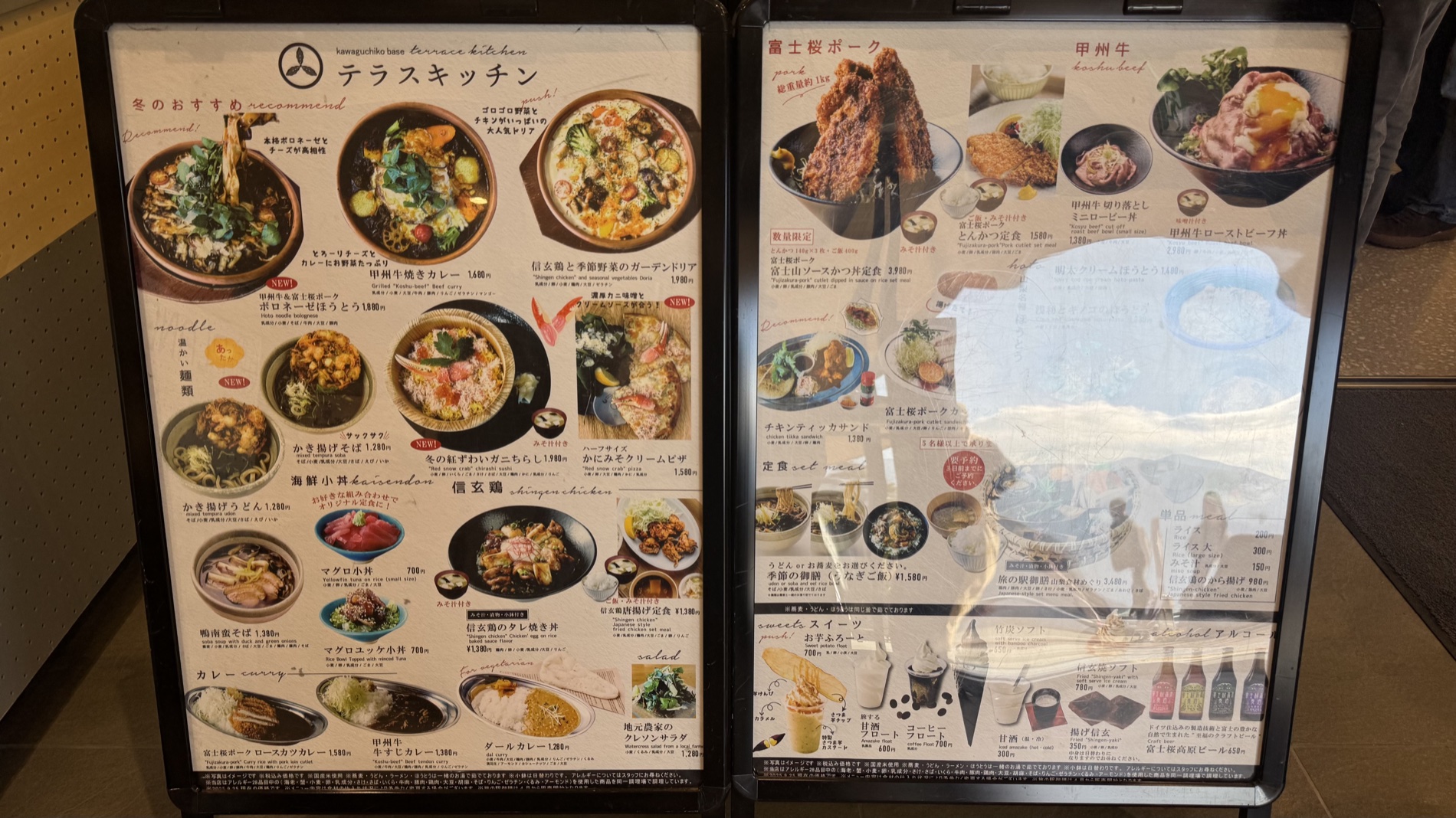 A menu board at Terrace Kitchen showing Fujizakura-pork and Koshu-beef dishes with photos and prices, Tabi-no-Eki Kawaguchiko Base.