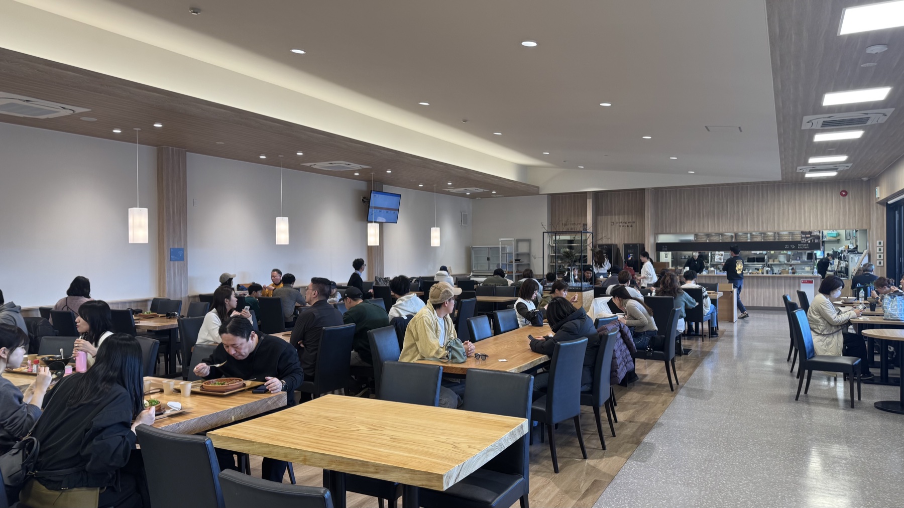 The spacious wood-toned interior of Terrace Kitchen restaurant with diners seated at tables, Tabi-no-Eki Kawaguchiko Base, Lake Kawaguchiko.