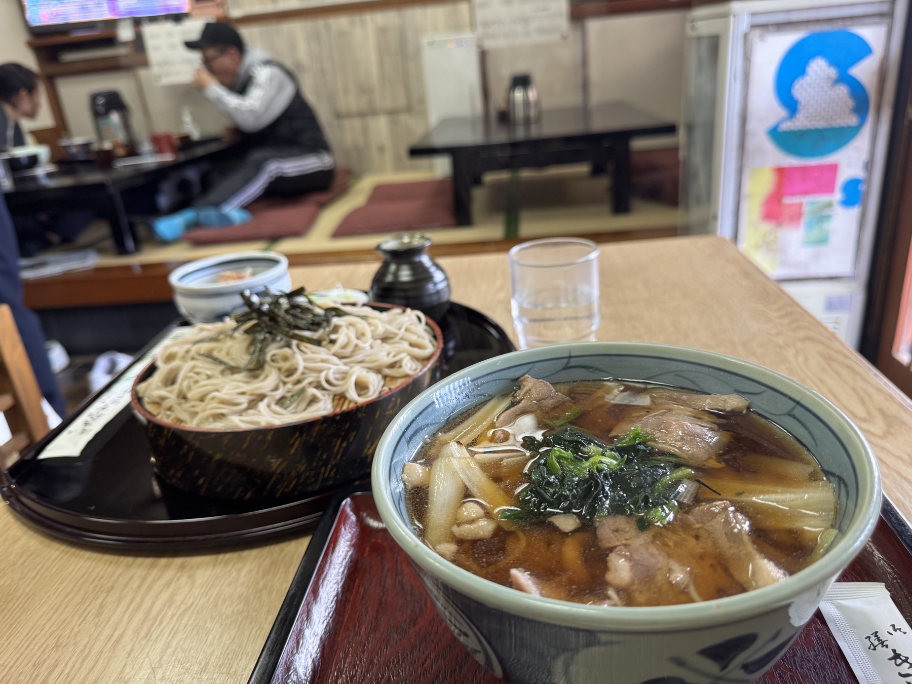 The duck soba set at Takinoya with the tatami zashiki seating area visible behind, where a customer sits at a low table in the old soba shop in Mitaka.