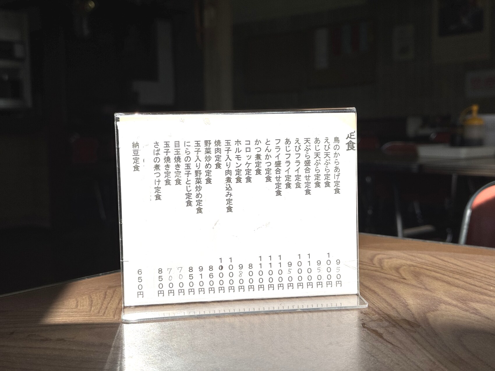 The hand-written teishoku menu board at Tatsumi Shokudo in Susono listing set meals such as tonkatsu, horumon, meat-and-egg stew, tempura and fried fish, with prices roughly 650 to 1,050 yen.