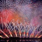 A wide star-mine of red, orange and silver fireworks fills the night sky and reflects across the dark surface of the Tone River at the Sakai Grand Fireworks festival in Ibaraki, Japan.