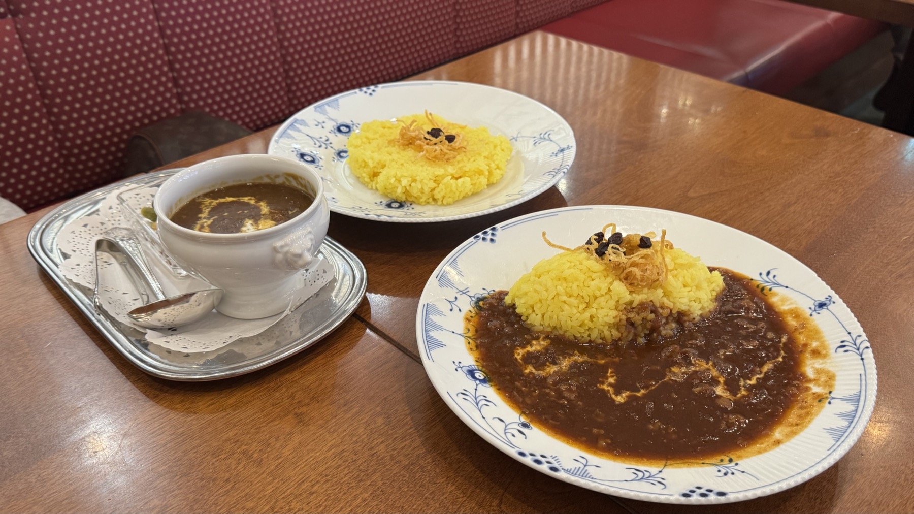 Two plates at Tsubakiya Cafe Kichijoji on Royal Copenhagen blue-fluted china, turmeric-yellow rice topped with crispy fried onion beside dark beef curry and hayashi sauce, with a small soup cup and pickles on a silver tray