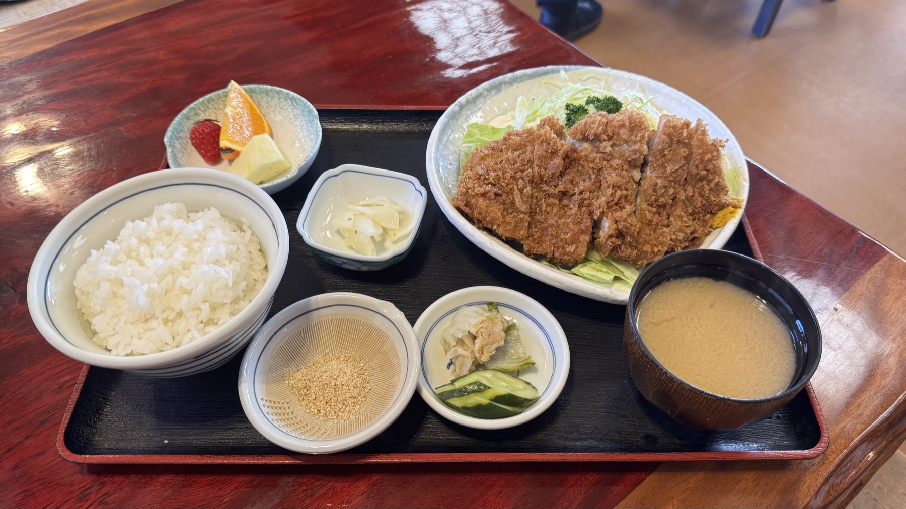 A tonkatsu set meal at Yabu in Fujiyoshida: a crisp panko-breaded pork cutlet on shredded cabbage with rice, miso soup, sesame, pickles and fresh fruit on a lacquer tray