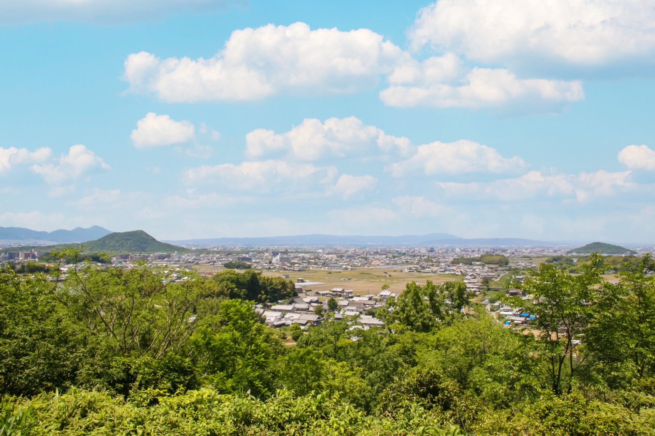 View from Amakashi Hill over the green Asuka and Kashihara plain with the volcanic hills of Mount Unebi and Mount Miminashi rising from the fields