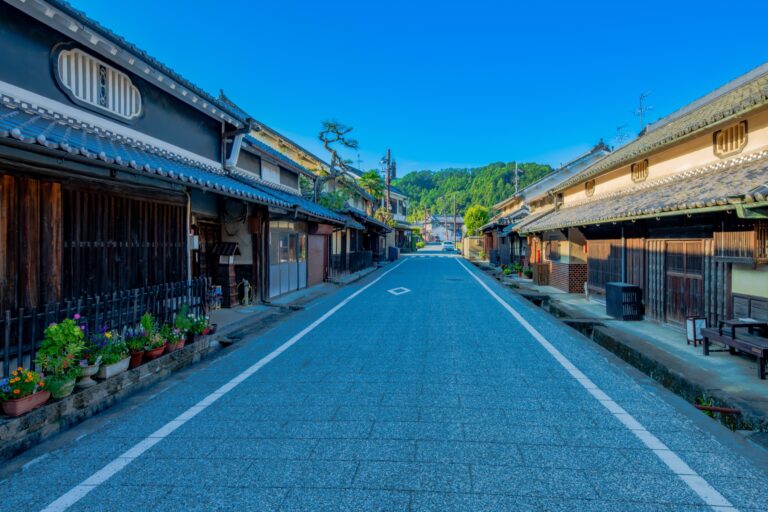 A quiet street through the old townscape of the Oka district in Asuka village Nara lined with traditional tile-roofed white-plastered houses with latticed fronts and green hills behind