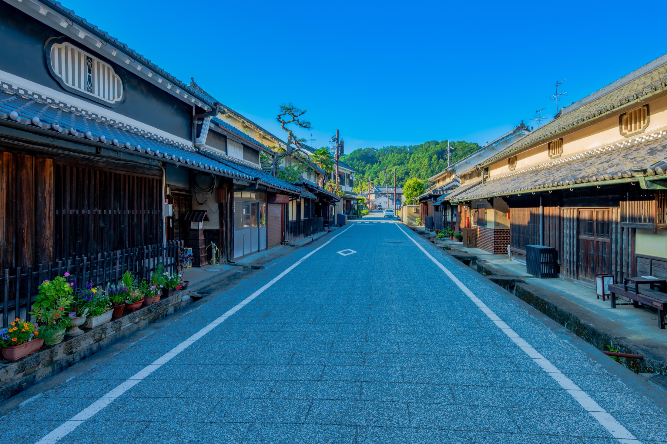 A quiet street through the old townscape of the Oka district in Asuka village Nara lined with traditional tile-roofed white-plastered houses with latticed fronts and green hills behind