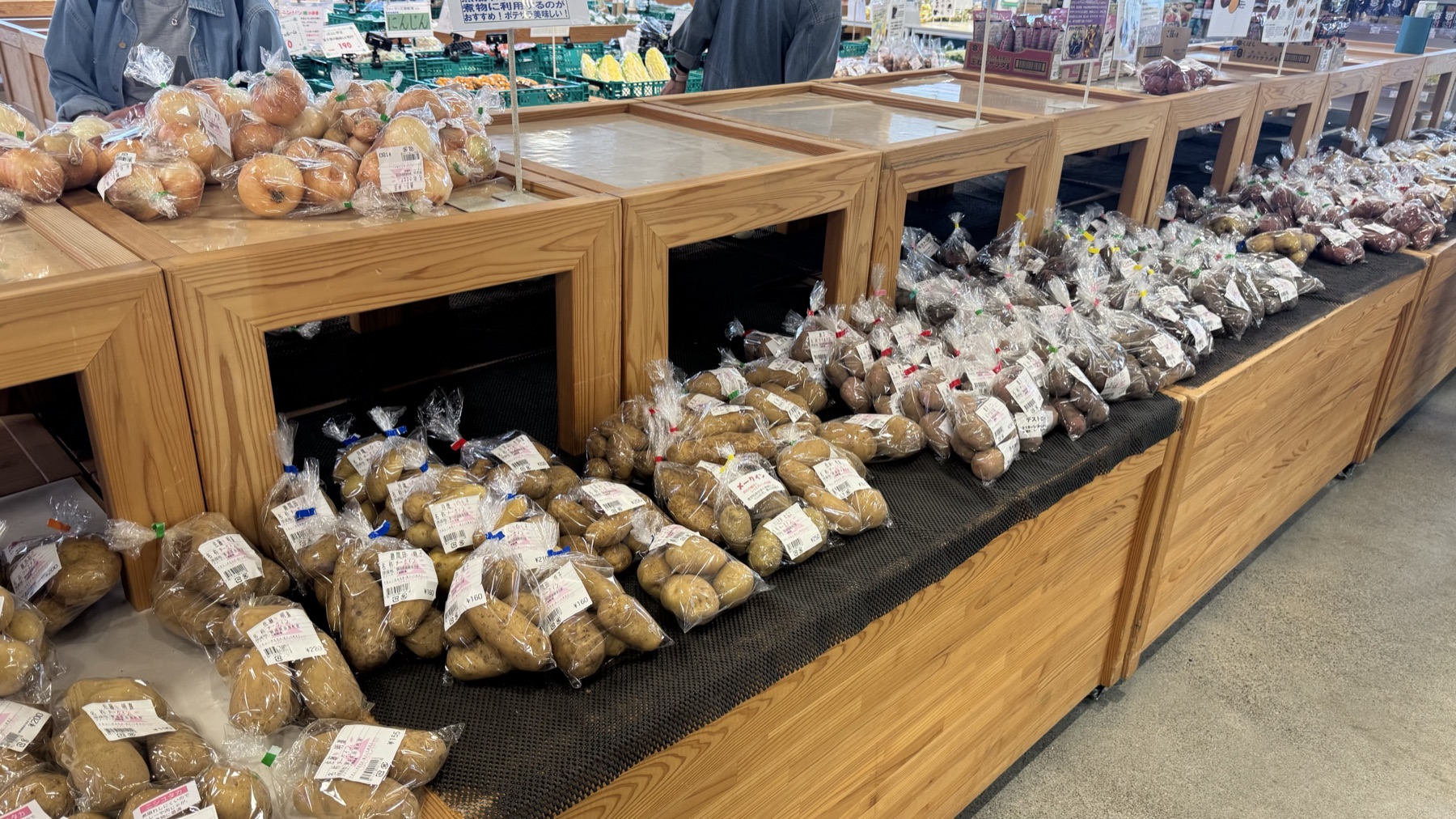 Bagged local potatoes and onions on a wooden display in the vegetable section of the JA Fuji-Izu Farmers Gotemba direct-sales market in Gotemba, Shizuoka