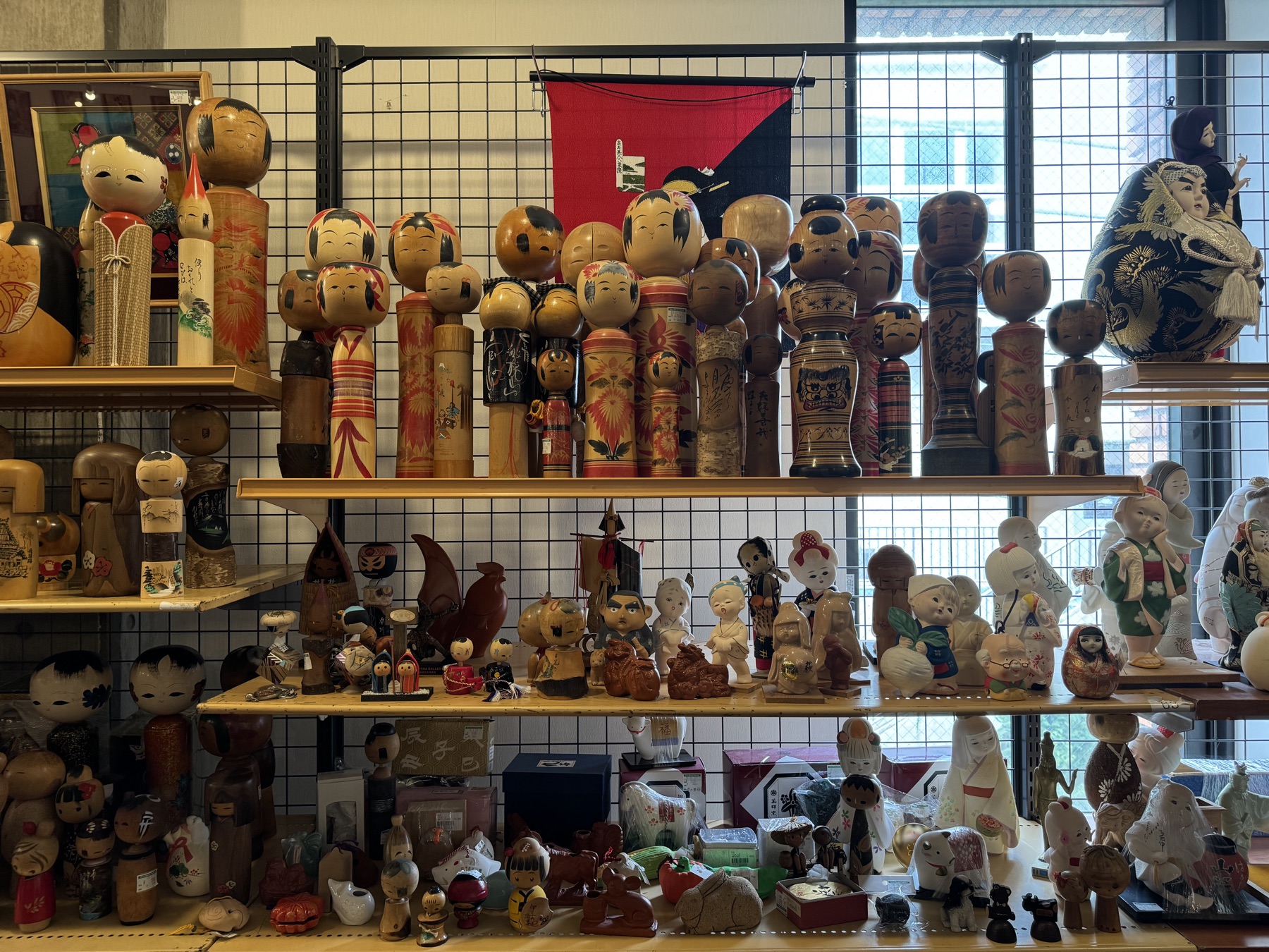 A shelf wall of traditional wooden kokeshi dolls and small folk figurines for sale in the secondhand Off House store at the Hachioji Owada reuse complex in western Tokyo