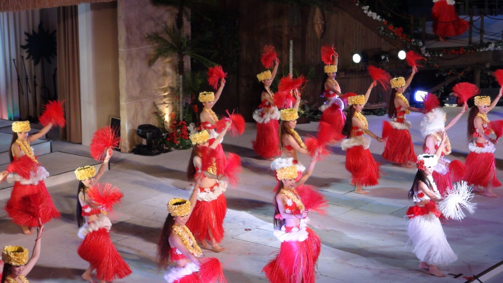 Rows of dancers in red-and-white hula costumes and headpieces performing the Polynesian show on stage at Spa Resort Hawaiians