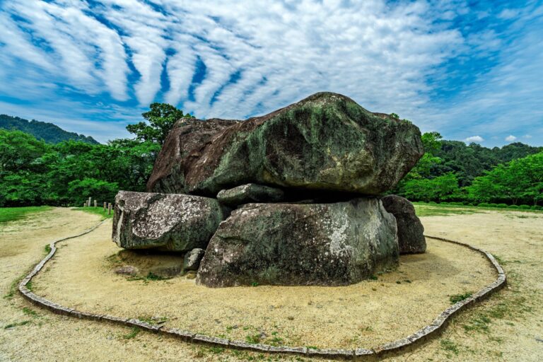 The exposed megalithic stone chamber of Ishibutai Kofun in Asuka village Nara, thirty massive rocks stacked into a seventh century tomb under a dramatic summer sky