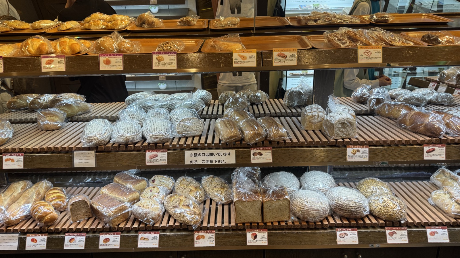 Shelves of dense German rye loaves in bags with handwritten price tags at Linde Kichijoji