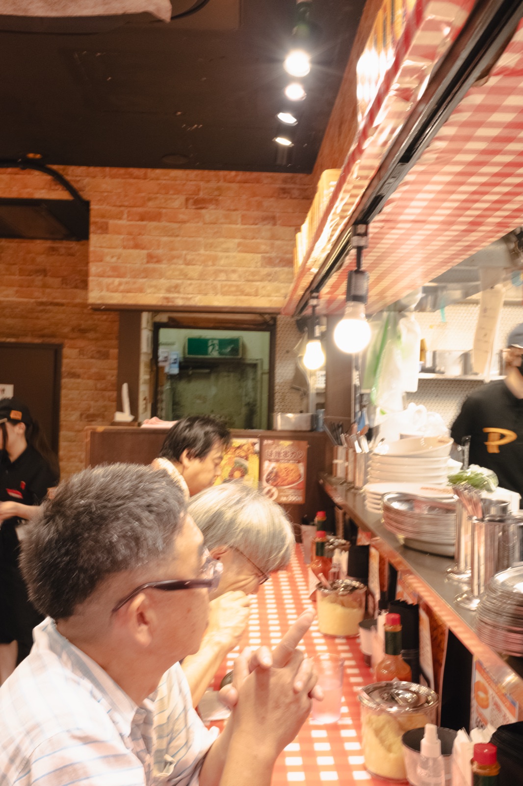 Counter seating with red gingham and a brick wall inside Pancho Kichijoji