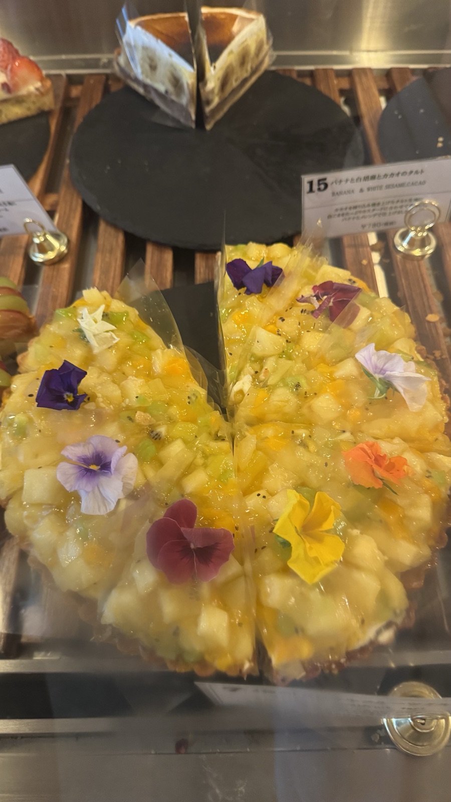 A colorful fruit tart topped with edible flowers at Princess Tart Kichijoji