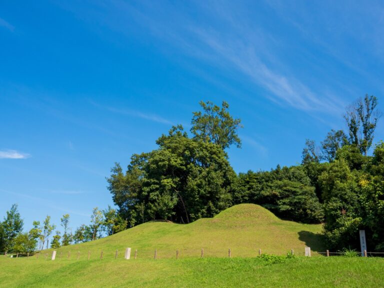 The restored grassy burial mound of Kitora Tomb in Asuka village under a blue summer sky, part of the Asuka-Fujiwara World Heritage property