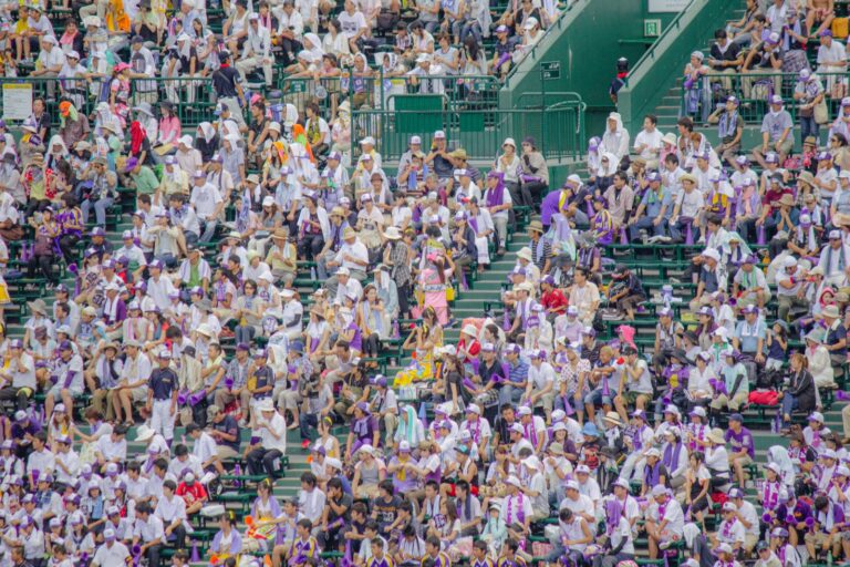 A packed alps stand of cheering fans in the summer heat at Hanshin Koshien Stadium