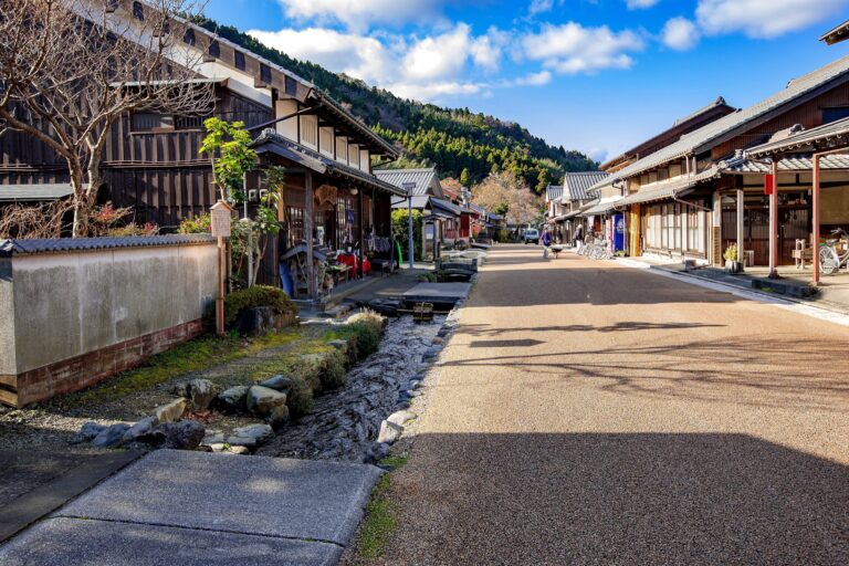 The main street of Kumagawa-juku on the Saba Kaido in Fukui with the clear Maegawa water channel running along the right side traditional machiya and mountains behind
