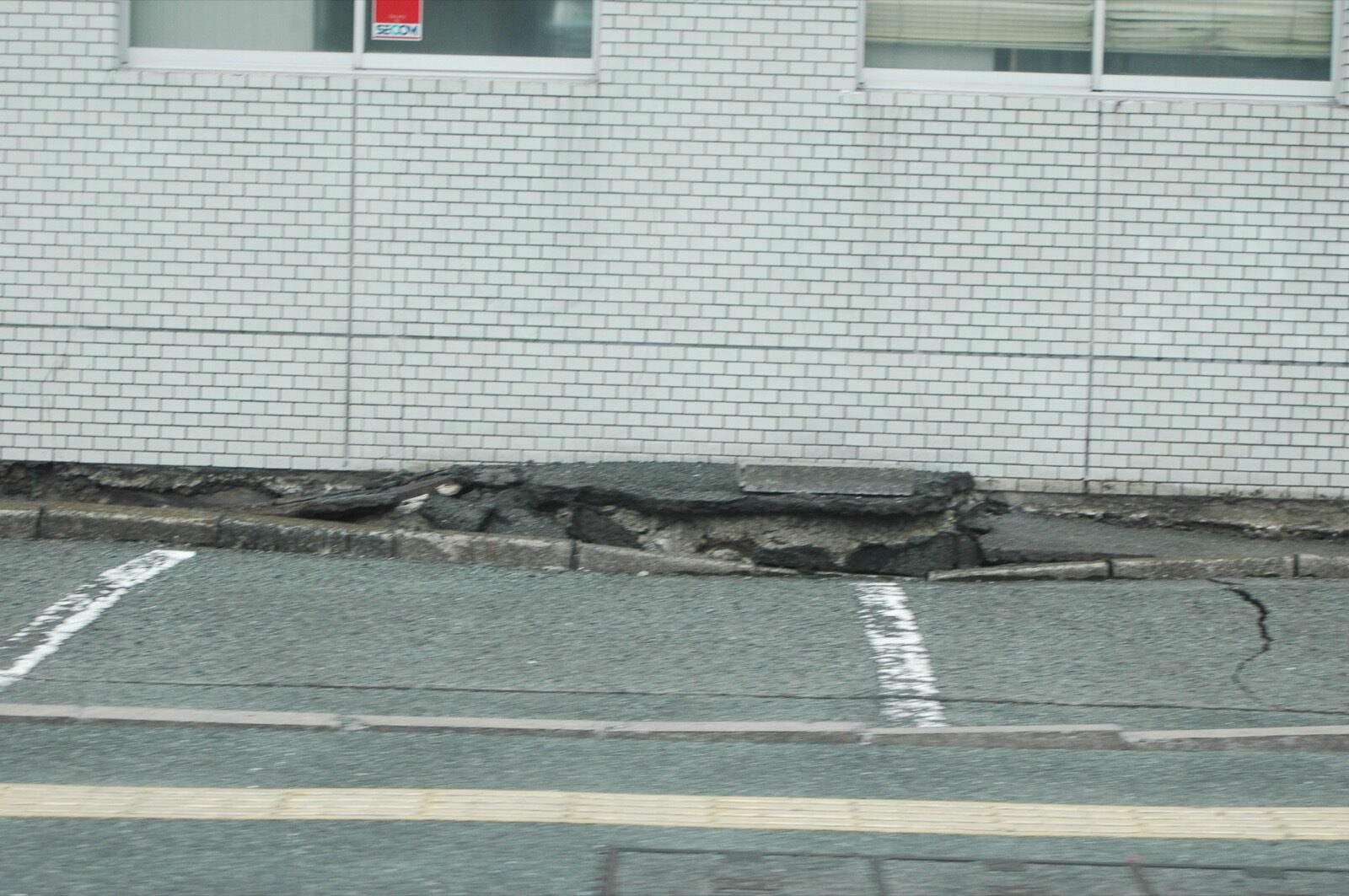 A road surface cracked and pushed upward into a ridge beside a building after the April 2016 Kumamoto earthquake