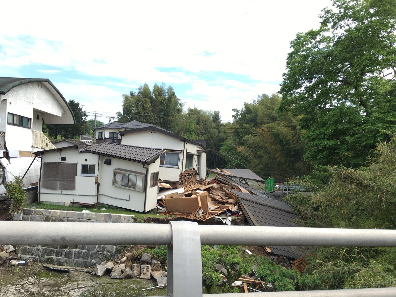 A house collapsed into rubble beside a river and a bridge railing after the April 2016 Kumamoto earthquake
