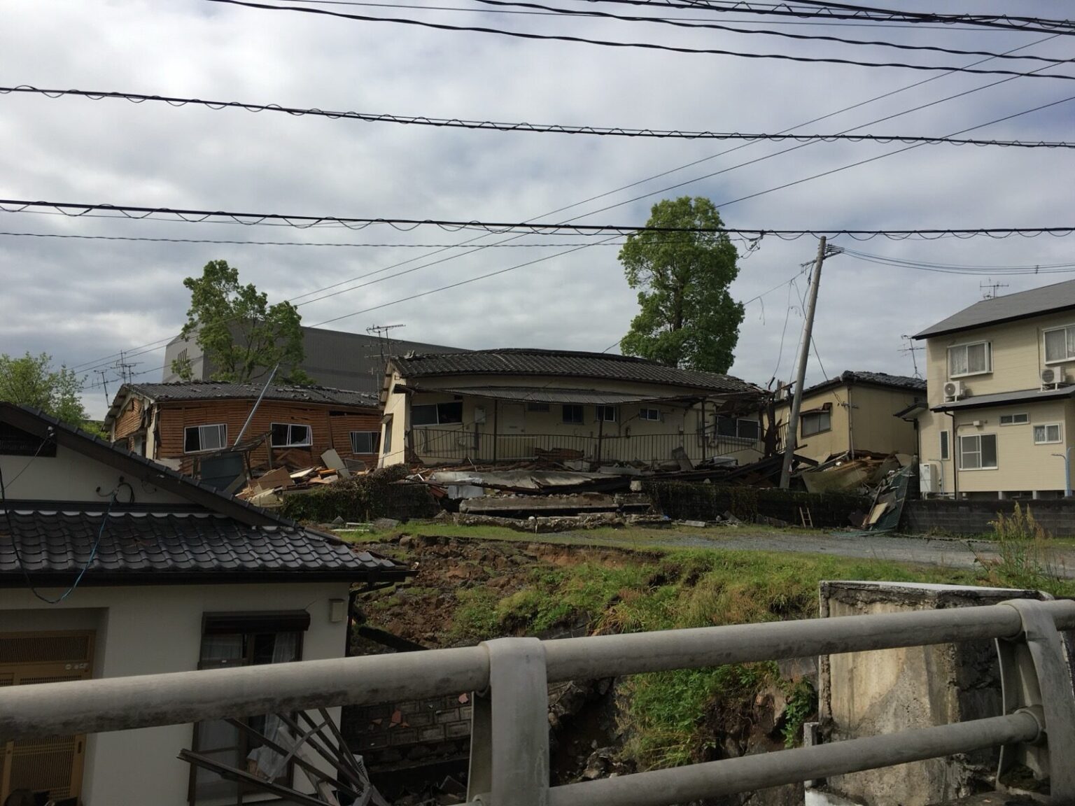 A collapsed house among power lines and neighbouring homes in a residential area after the April 2016 Kumamoto earthquake