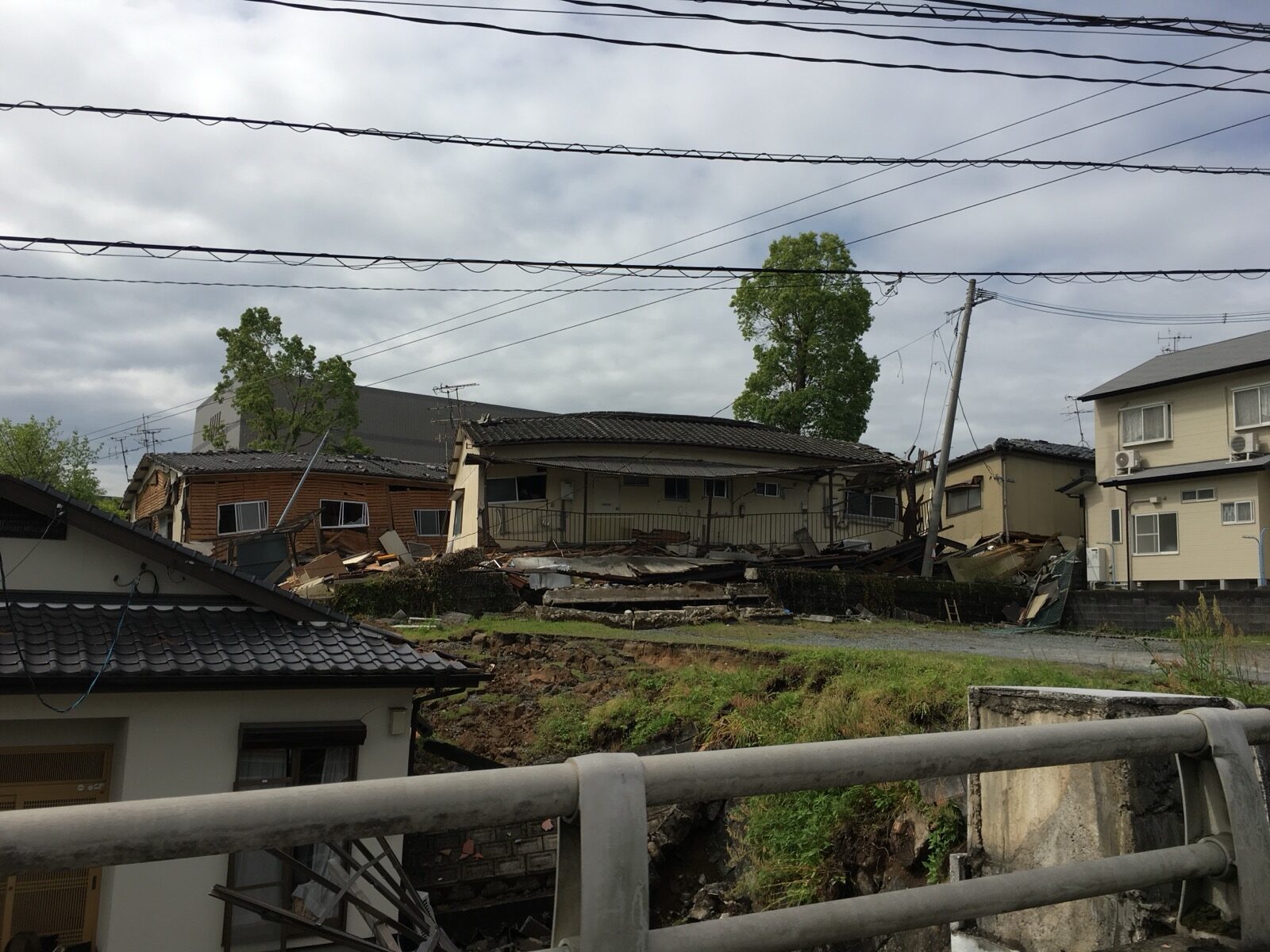 A collapsed house among power lines and neighbouring homes in a residential area after the April 2016 Kumamoto earthquake
