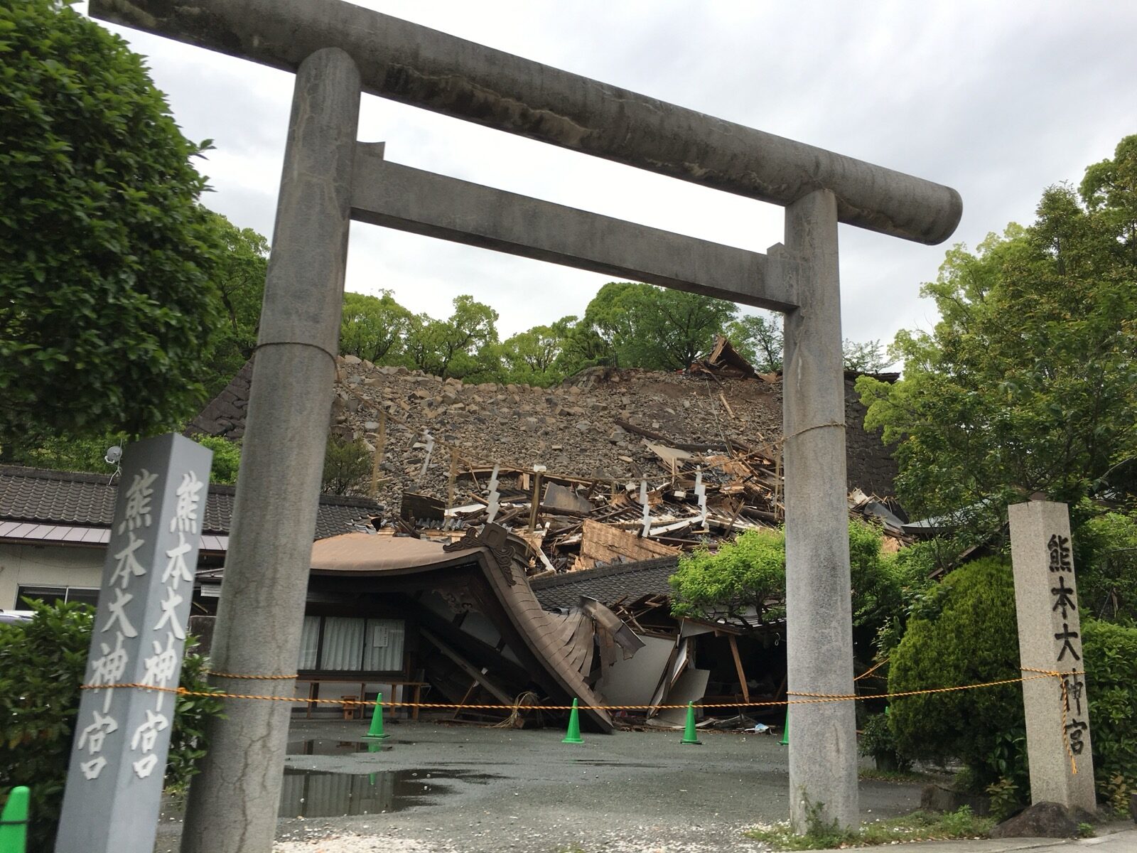 A stone torii gate still standing in front of the completely collapsed hall of Kumamoto Daijingu shrine after the April 2016 earthquake