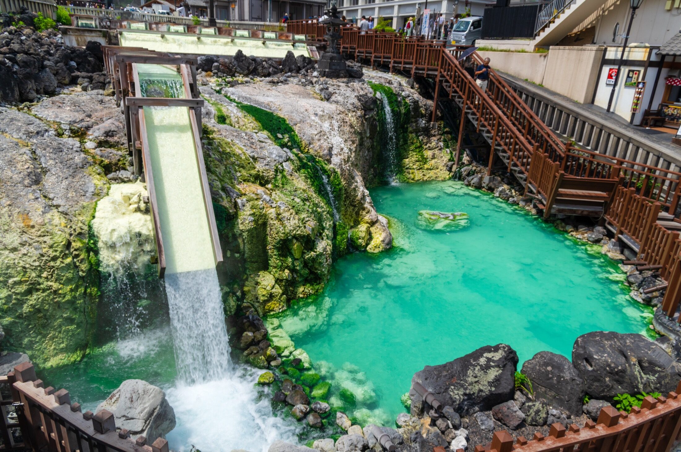 The Yubatake hot spring field in the centre of Kusatsu Onsen with turquoise mineral water flowing down wooden channels on a clear summer day