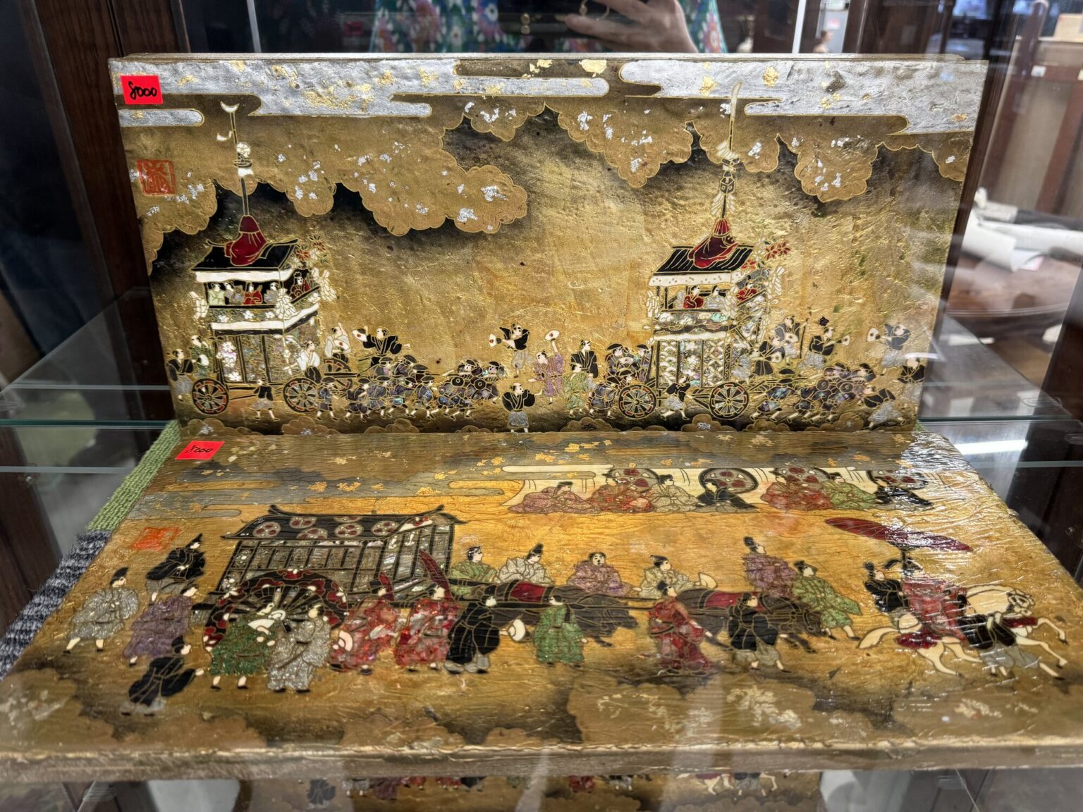 A gold-leaf lacquer panel depicting a townscape, displayed in a glass case at a Kyoto secondhand shop, the kind of one-off antique that turns up among everyday goods.