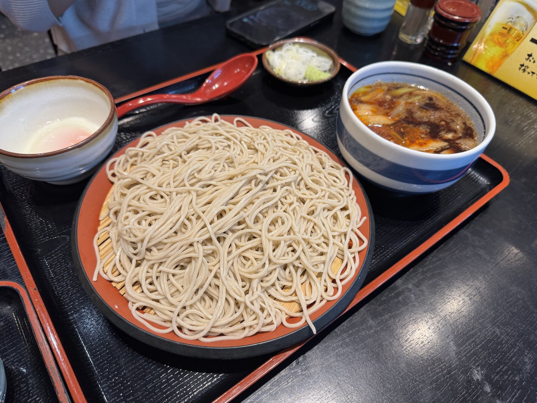 A pork seiro (buta seiro) set at Minatoan Konandai in Yokohama, with a large plate of freshly boiled cold soba beside a bowl of hot pork dipping broth and side dishes on a lacquer tray.