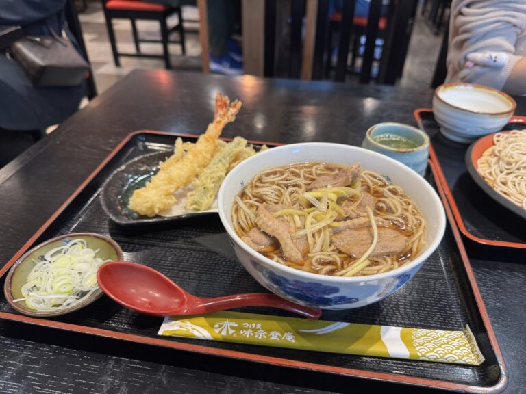 A duck seiro (kamo seiro) set at Minatoan Konandai in Yokohama: cold buckwheat soba, a bowl of hot duck-and-leek dipping broth, and a plate of shrimp and vegetable tempura on a black tray.