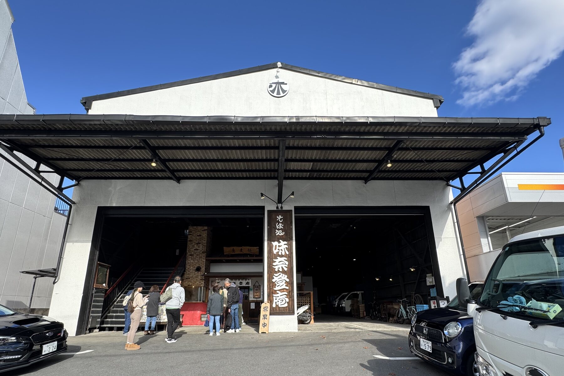 The warehouse-style Minatoan Konandai soba restaurant in Yokohama, a large gabled building with the shop's banner at the entrance and a car park in front, on the Konandai roadside.