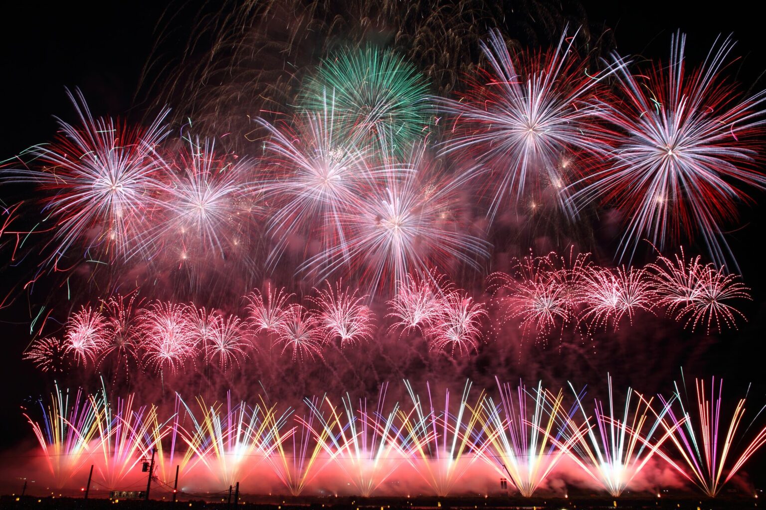 Layered red white and green competition fireworks filling the sky above the Omono River at the All-Japan National Fireworks Competition in Omagari, Akita