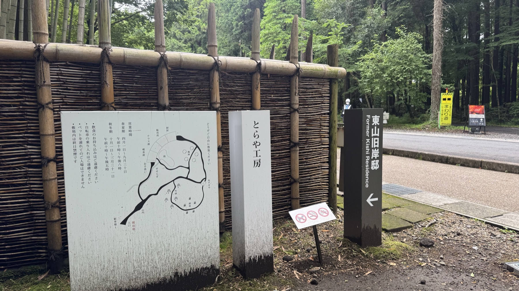 The entrance to Toraya Kobo with a bamboo-and-brushwood fence, a stone marker and a signpost pointing to the neighbouring Higashiyama Former Kishi Residence in Gotemba