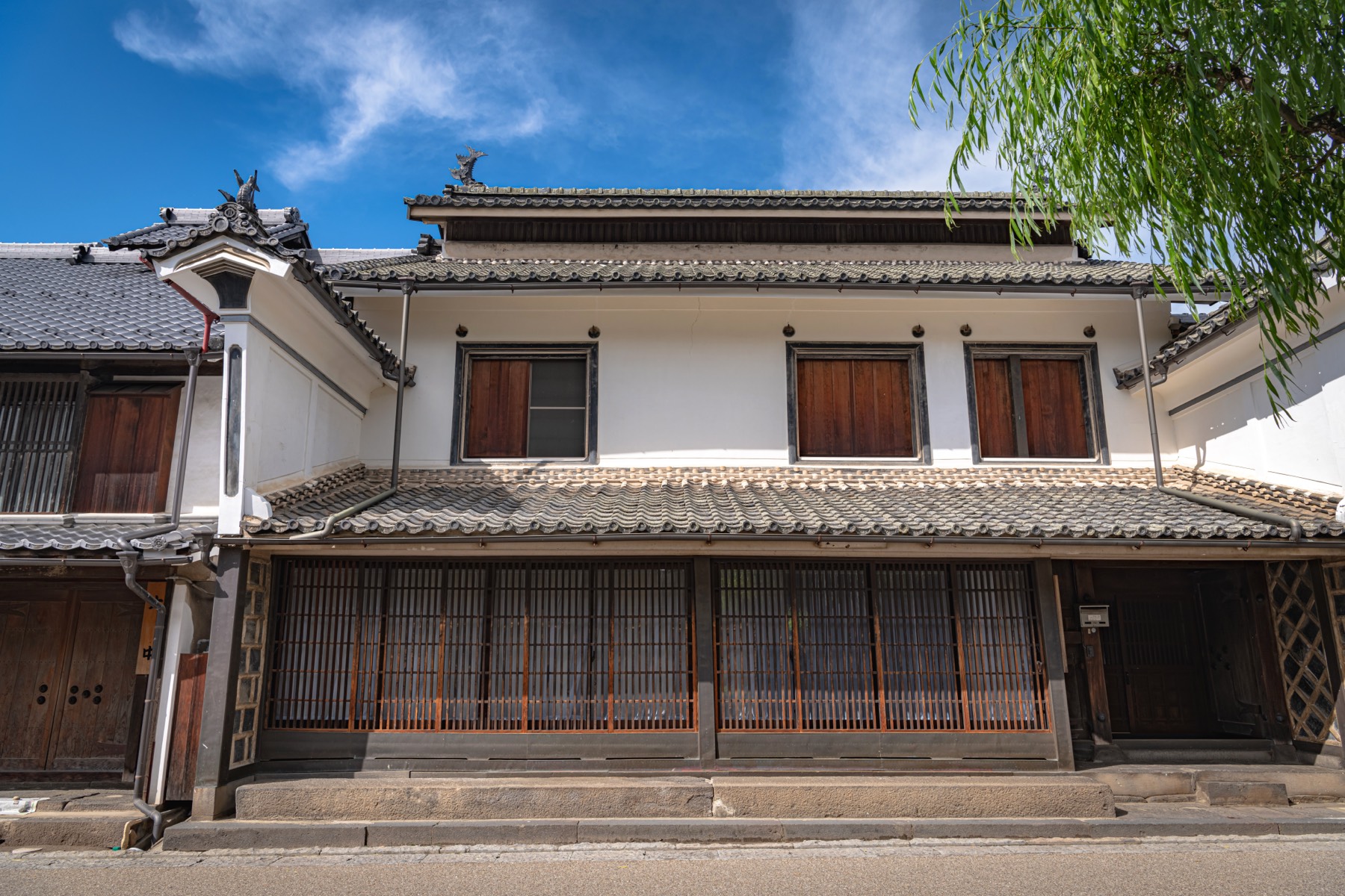 A grand two-storey Edo and Meiji era house in Unno-juku with white plaster upper wall family crest a projecting udatsu fire wall and fine Unno-goshi wooden lattice across the ground floor