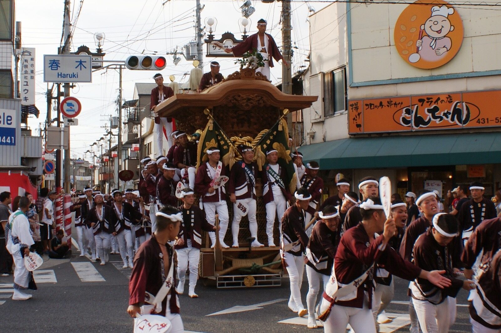 A wooden danjiri float with people riding on its roof during the Haruki district festival in Kishiwada