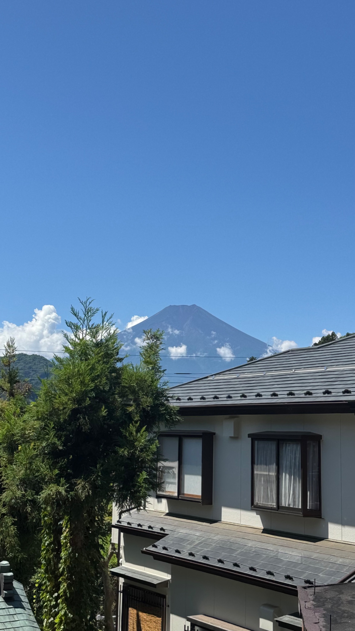 Mt. Fuji clearly visible from the Fujiyoshida side on the morning of 12 August 2026, the summit sharp above the town before the daytime cloud built