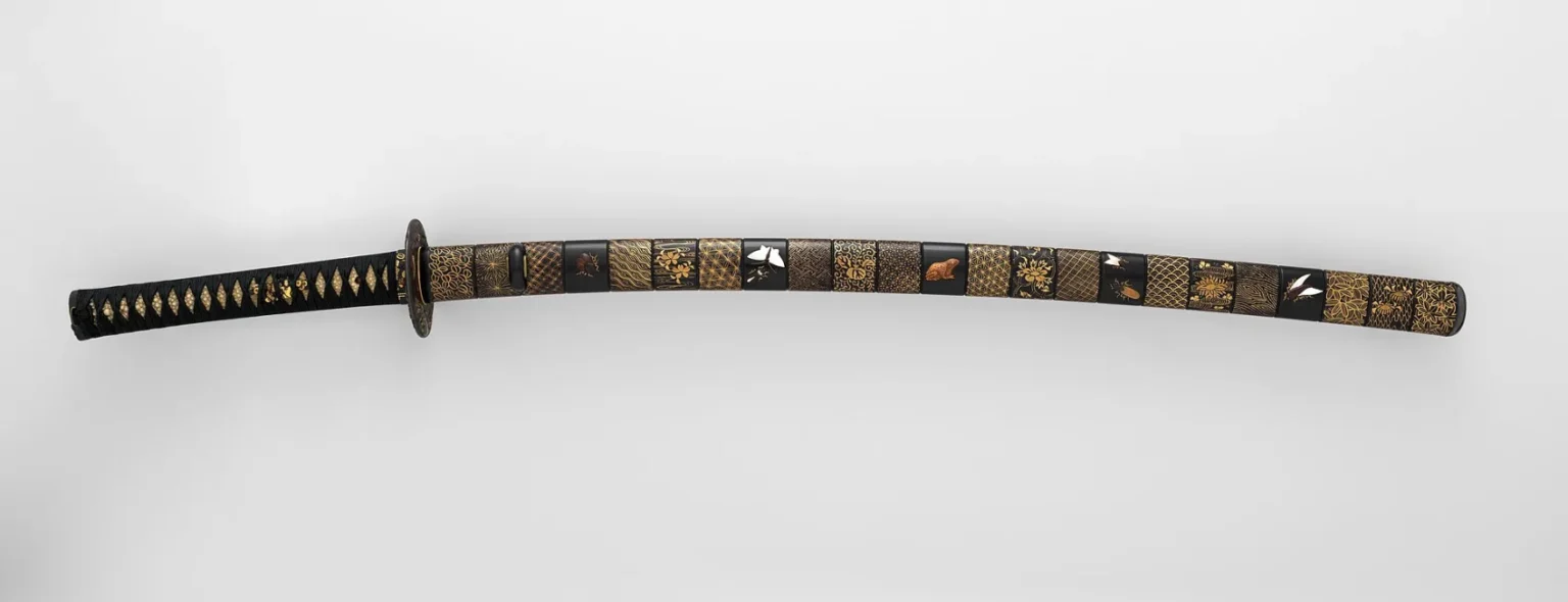 A Japanese katana sword in an ornate black-and-gold lacquered mounting, the kind of blade made from tatara-smelted tamahagane steel