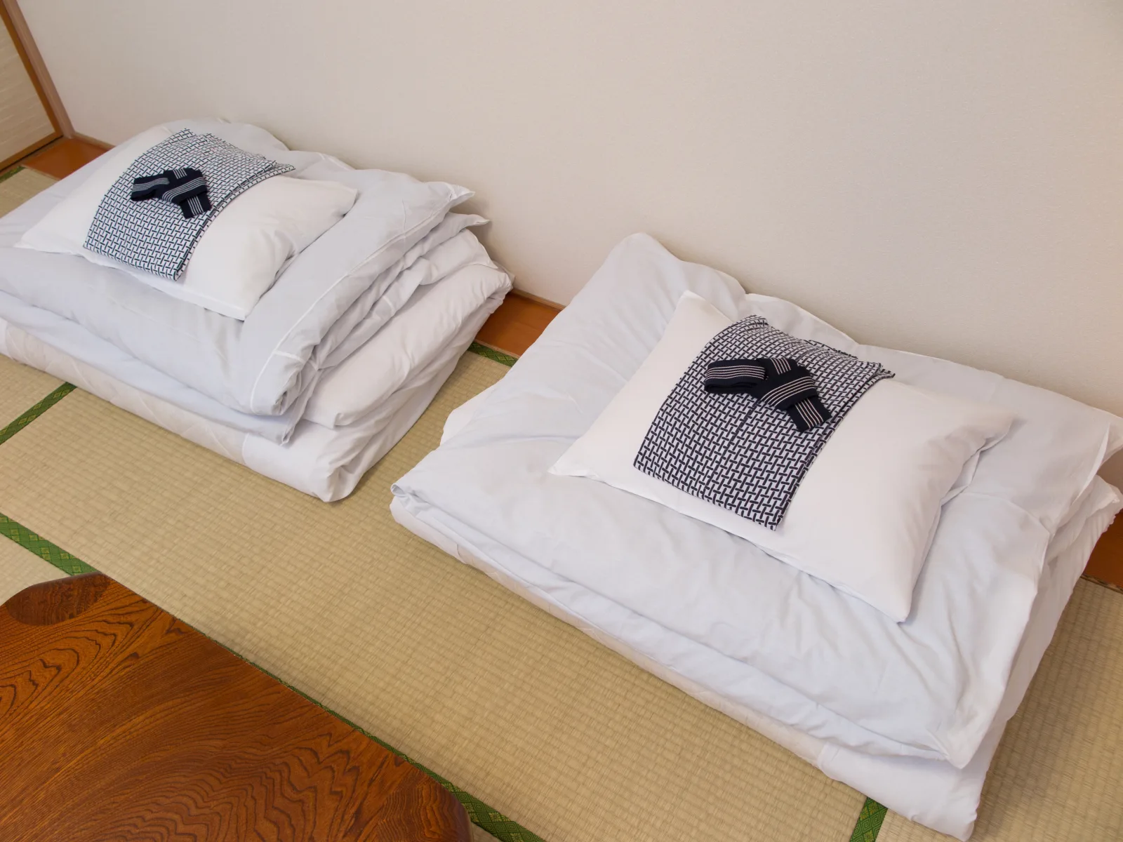 Folded futon bedding and a yukata robe laid out on tatami mats in a traditional Japanese ryokan guest room