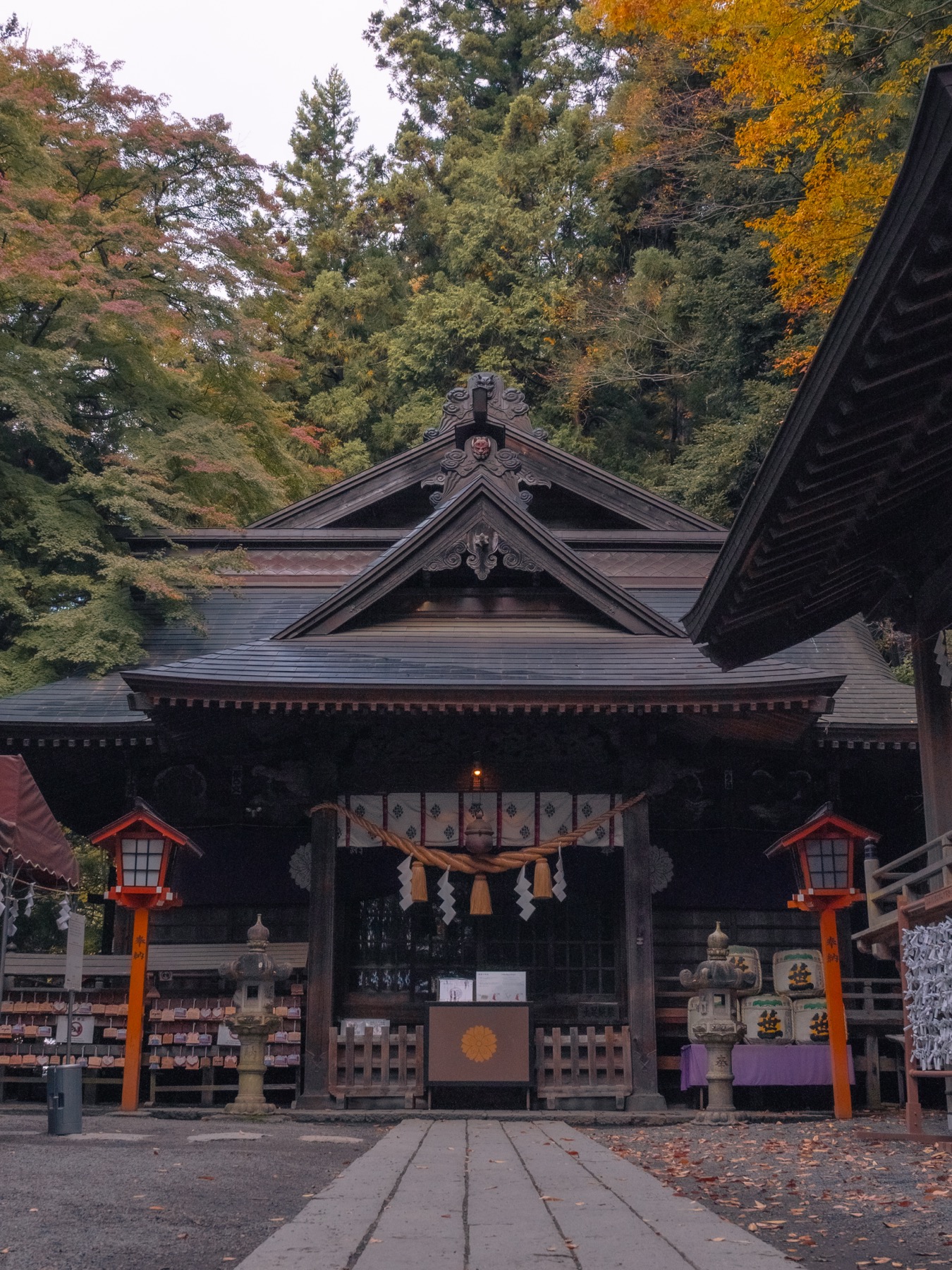 The wooden main hall of Arakura Fuji Sengen Shrine at the foot of the Chureito steps, framed by autumn leaves