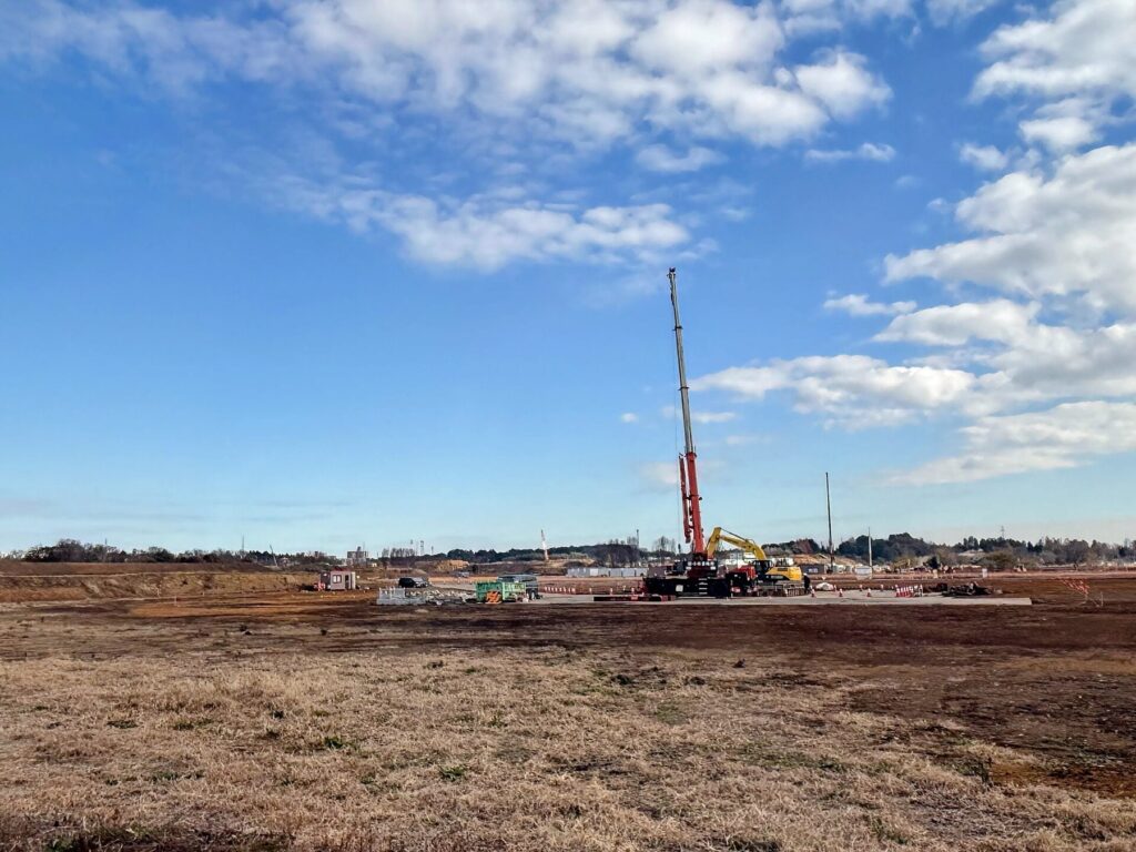 The GREEN×EXPO 2027 site at the former Kamiseya Communications Facility in Yokohama, still bare ground with a single crane, December 2025