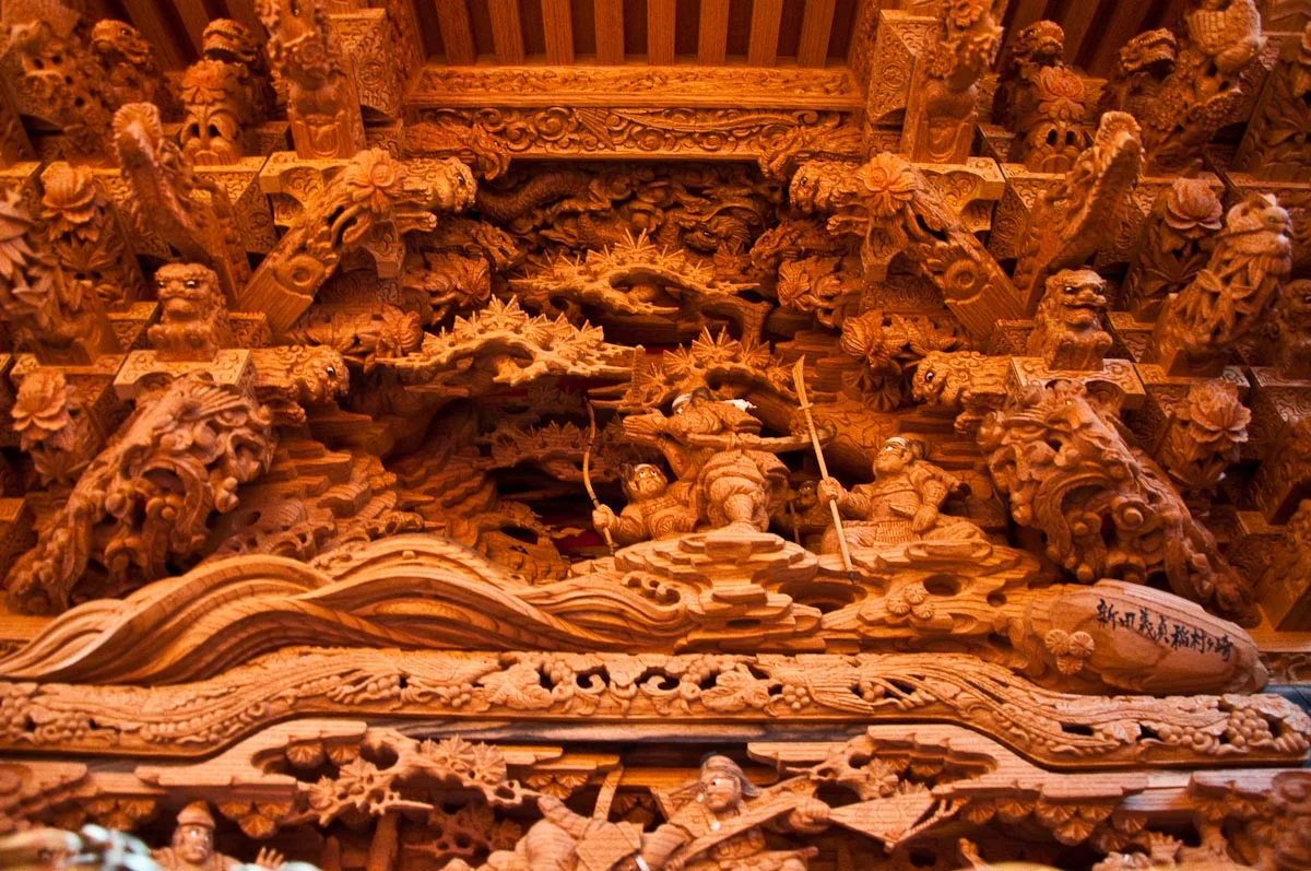 Dense carved woodwork of dragons, waves and warrior figures on the roof of a Kishiwada danjiri float
