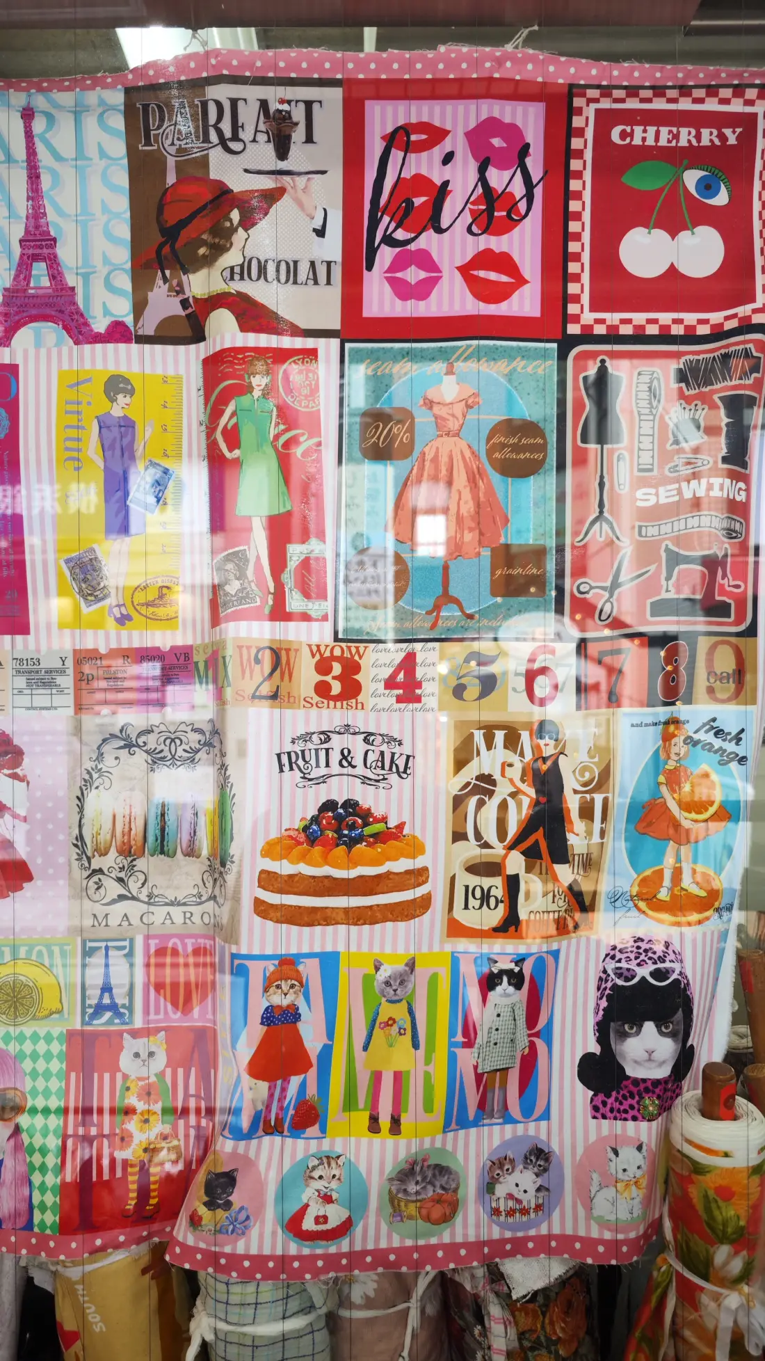 A wall of printed cotton fabric panels in Shimokitazawa showing cherries, cakes, Paris scenes and character prints, displayed side by side for sale.