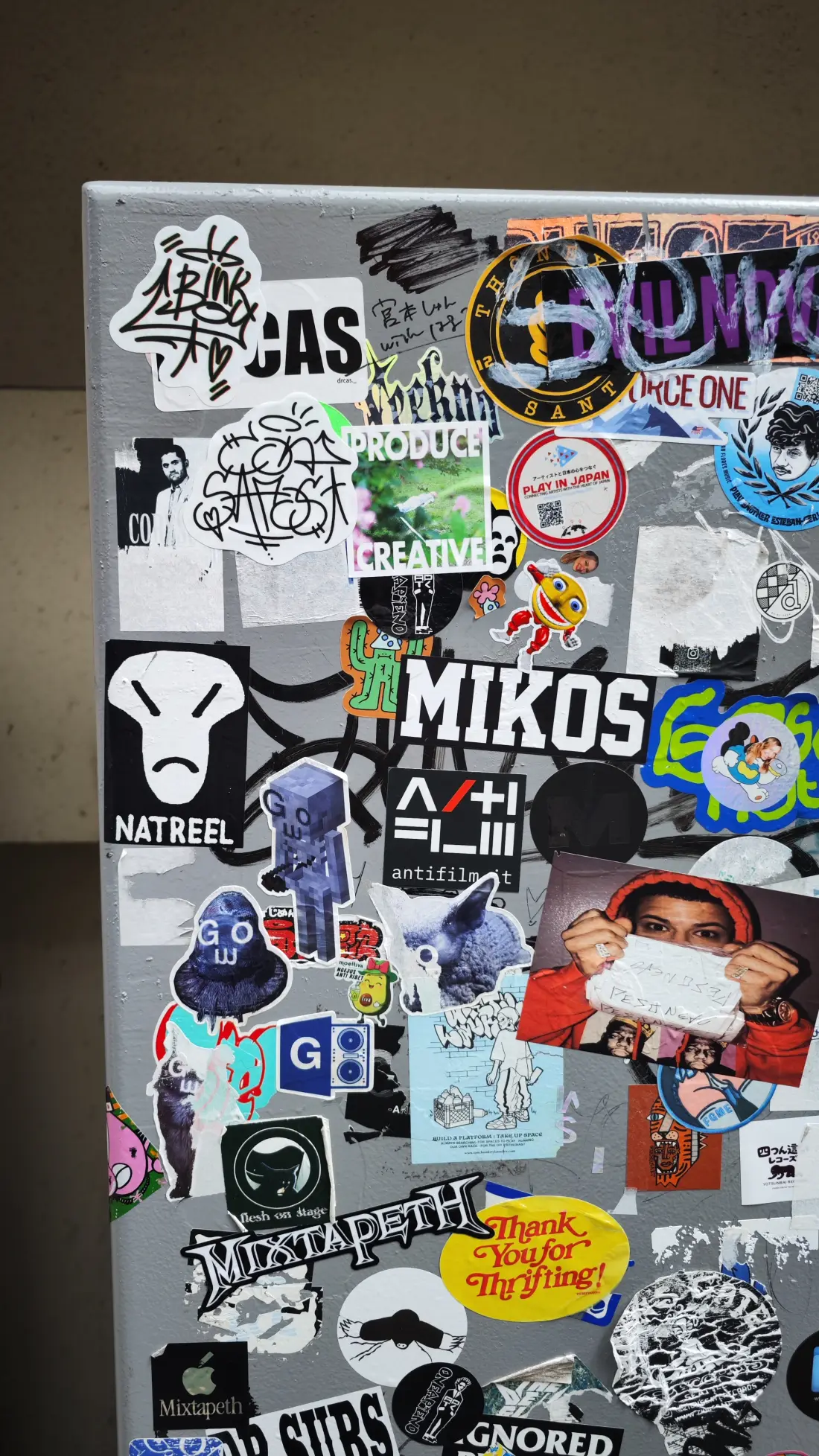 A street-side panel in Shimokitazawa covered in layered vinyl stickers, band logos and hand-drawn artwork.