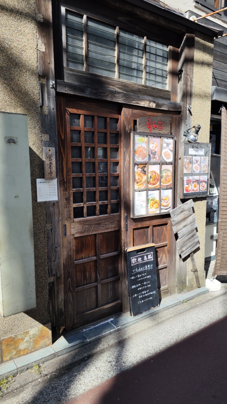 Dark wooden sliding door entrance of Yue He Cha in Kichijoji with photo menu boards and a chalkboard